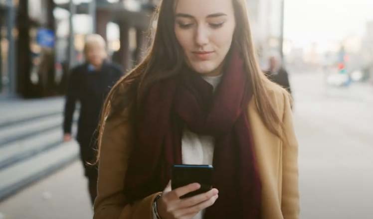 Young caucasian woman walking on the streets and using a credit card app built on top of all-in-one cloud native Pismo Platform